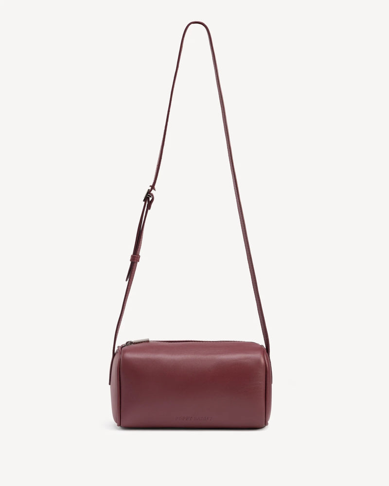Cylindrical barrel bag with long adjustable crossbody strap. The Annex Bag Compote.