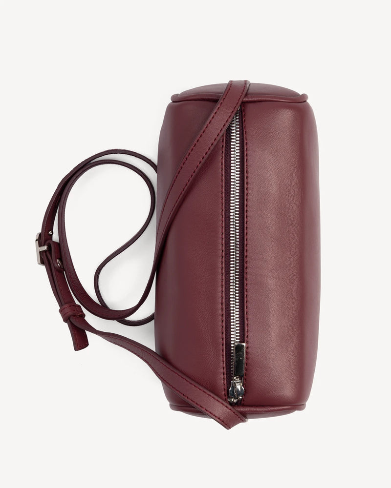 Side view of cylindrical barrel bag showing zip closure and strap. The Annex Bag Compote.