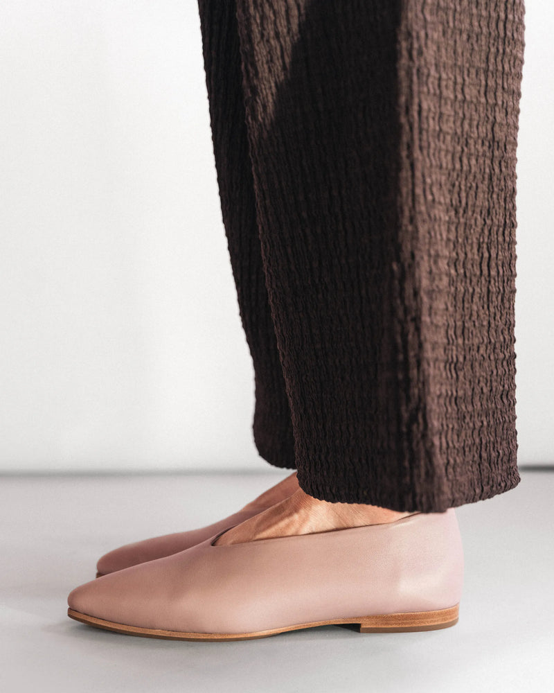 Leather pointed-toe flats, side view with dark textured trousers. The Atelier Flat Dusty Mauve. Sizes 5–12.