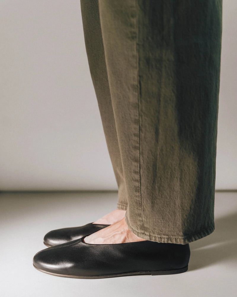 Leather ballet flats with round toe, side view with olive trousers. The Contemporary Ballet Flat Black. Sizes 5–12.