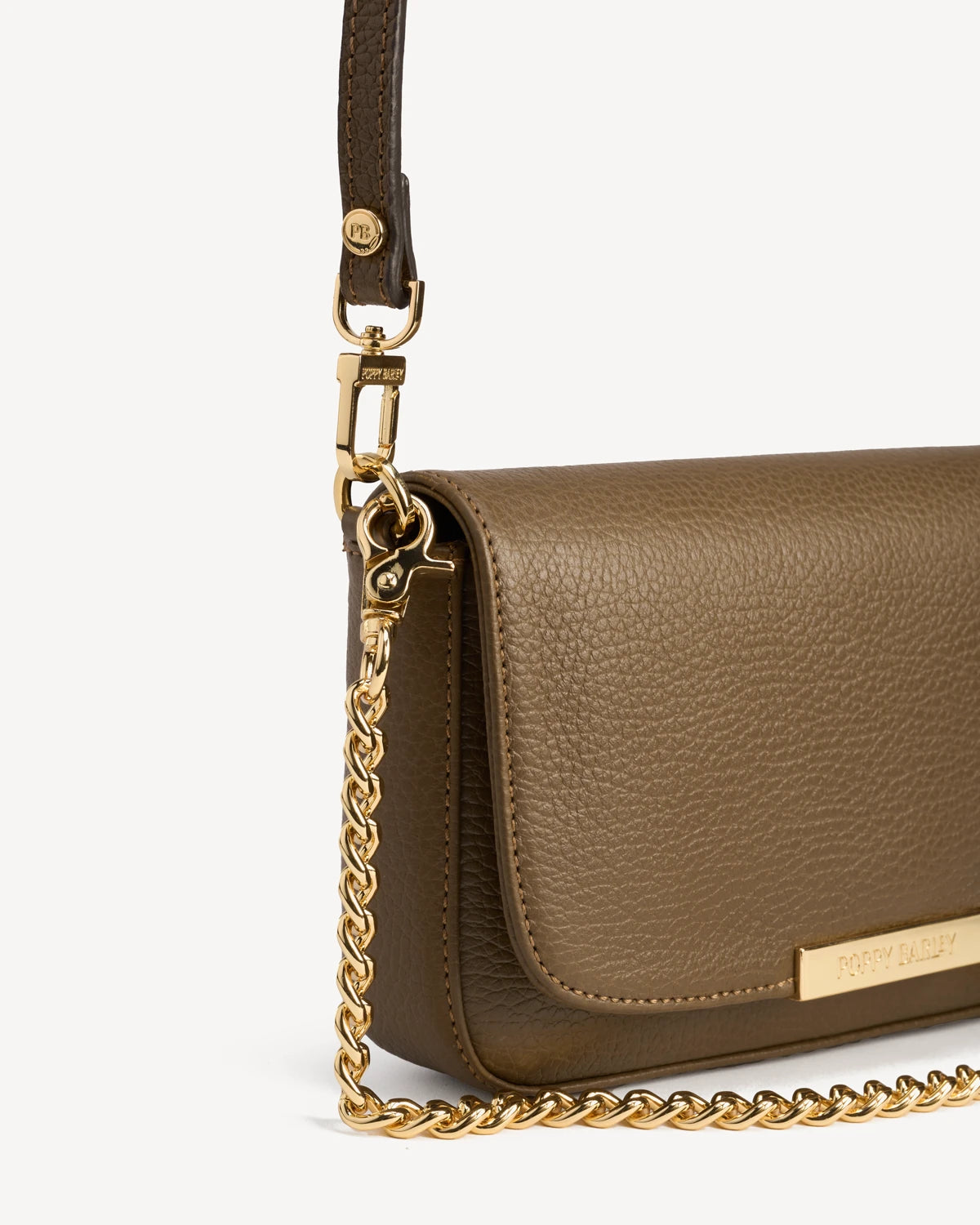 Close-up of the chain strap and flap closure on the leather bag. The Day To Night Bag Tapenade.