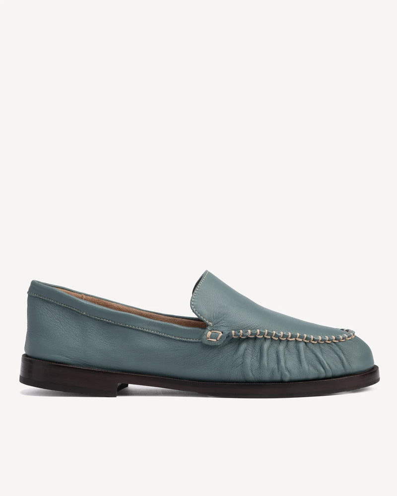 Side view of slip-on loafer with ruched vamp and chain trim. The Laid Back Loafer Storm. Sizes 5–12, wide available.