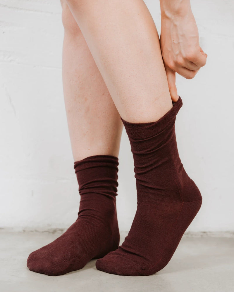 Close view of a hand pulling the crew sock up over the ankle. The Dressy Crew Sock Port.