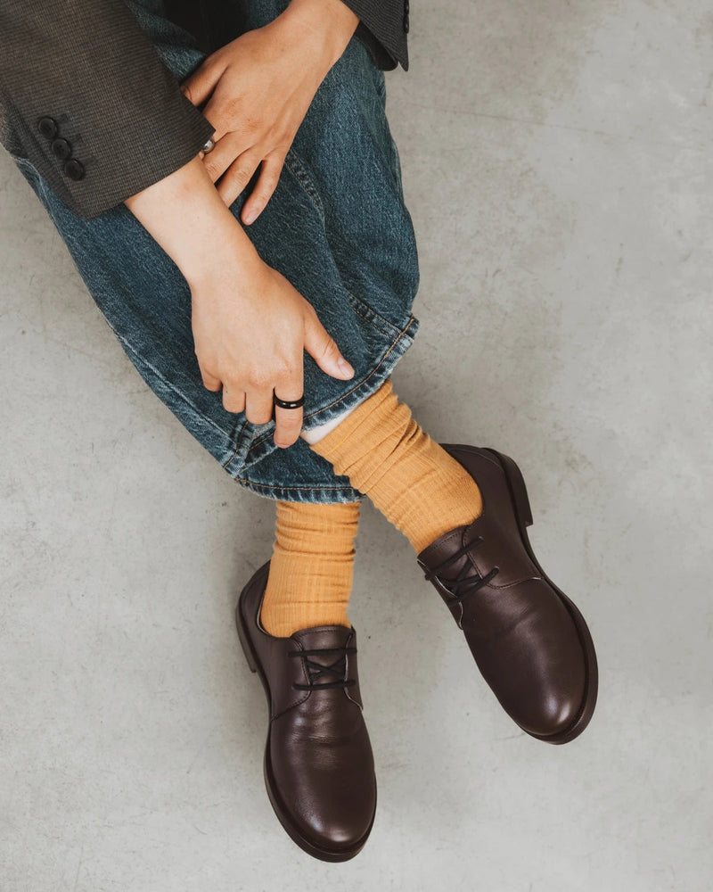 On-foot with brown lace-up oxfords, socks slouched at the ankle. The Ribbed Crew Sock Ochre.