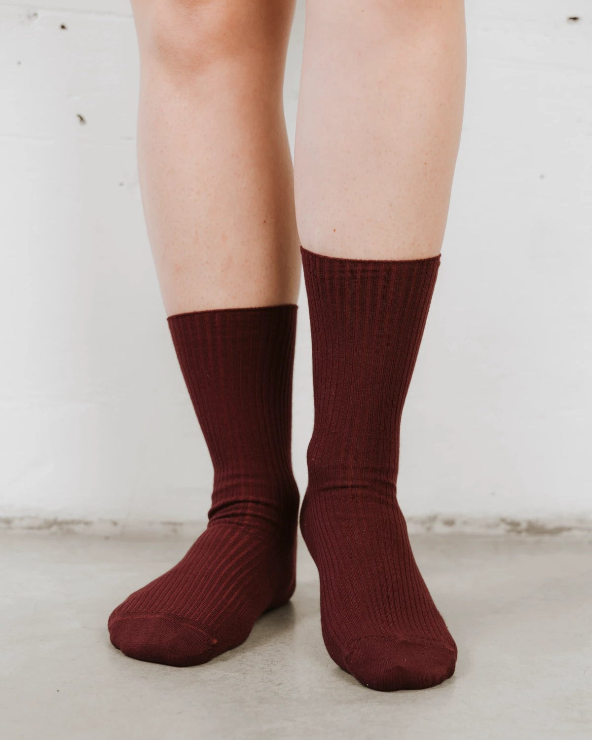 Close view of ribbed knit texture and folded cuff on bare legs. The Ribbed Crew Sock Sangria.