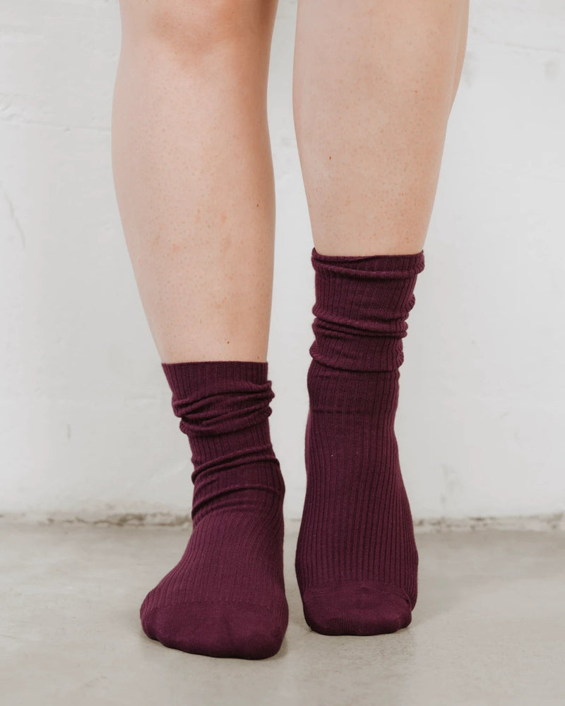 Back view of ribbed socks slouched at the ankle, cotton-rich knit with recycled fibers. The Ribbed Crew Sock Cassis.