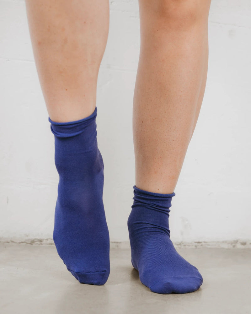 Back view, ankles crossed, folded cuff on soft cotton-rich knit. The Daily Mid Crew Sock Atlantic.