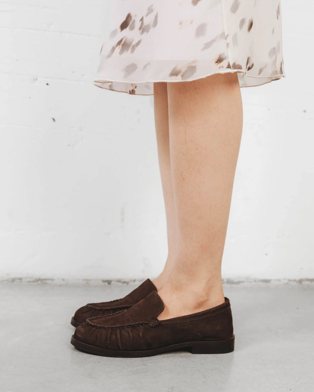 Close-up of a suede loafer worn with a printed dress. The Laid Back Loafer Cocoa Plum. Sizes 5–12, wide available.