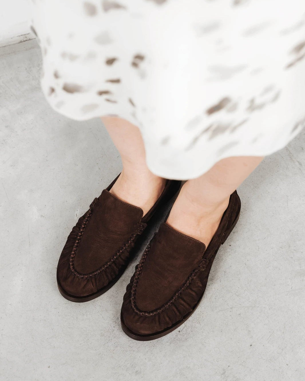 Close-up of suede loafers worn with a floral dress. The Laid Back Loafer Cocoa Plum. Sizes 5–12, wide available.