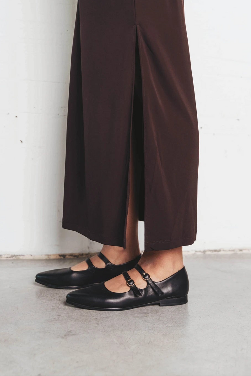 Leg shown wearing pointed-toe flats with double straps. The Editorial Mary Jane 2.0 Black. Sizes 5–12, wide available.