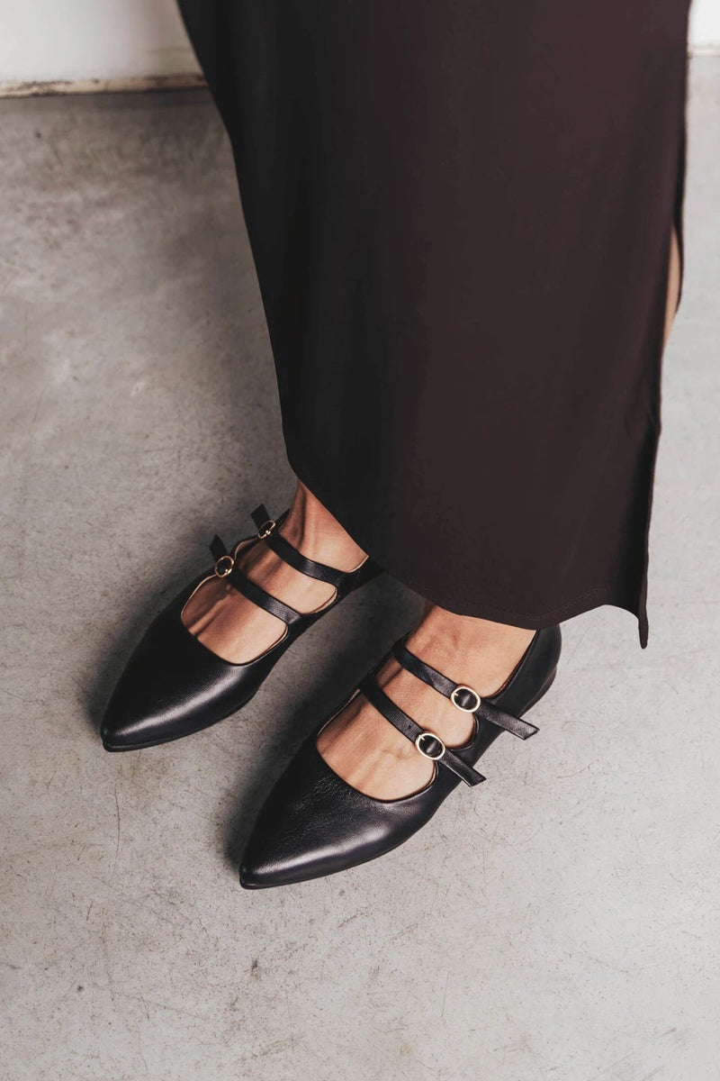 Feet in pointed-toe flats with double straps. The Editorial Mary Jane 2.0 Black. Sizes 5–12, wide available.