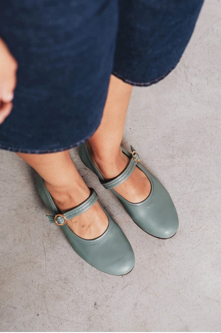Feet shown wearing round-toe flats with single buckle strap. The Modern Day Mary Jane Storm. Sizes 5–12.