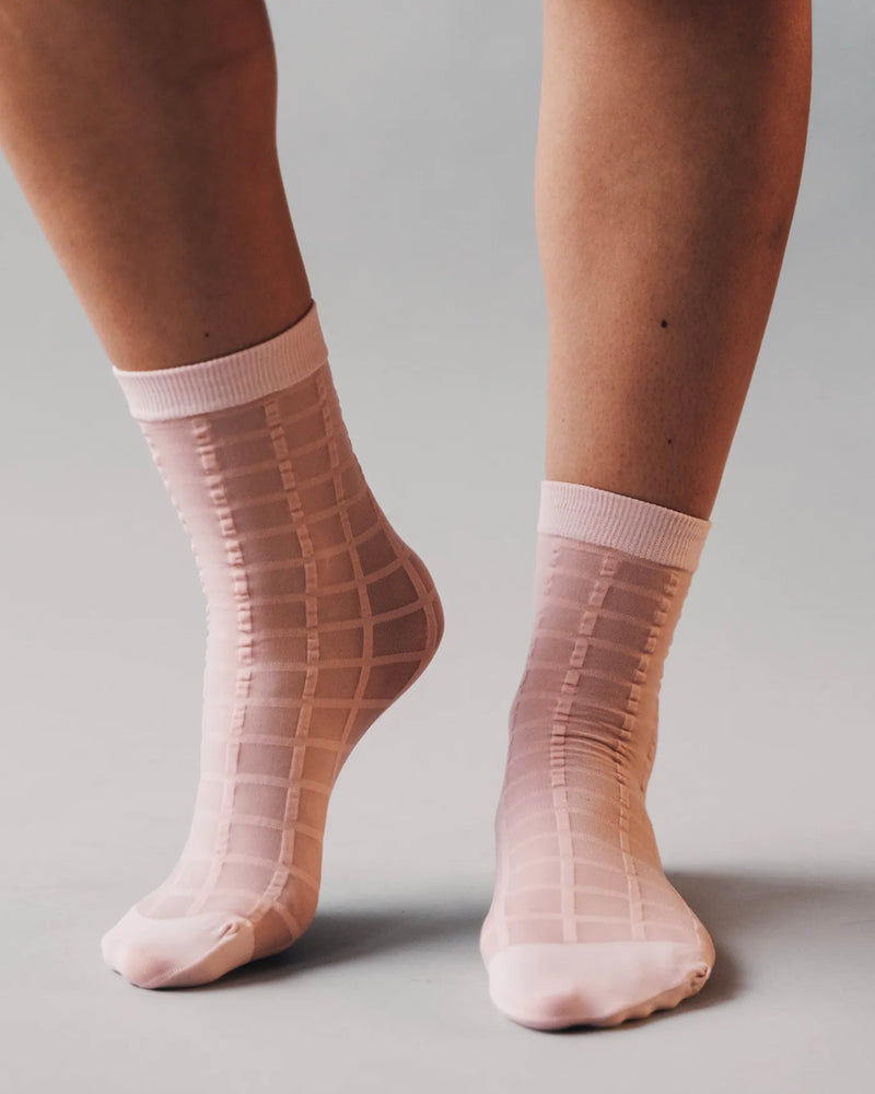 Checkered sheer ankle socks on woman's bare legs. Rachel Checkered Sheer Socks Ballerina Pink.