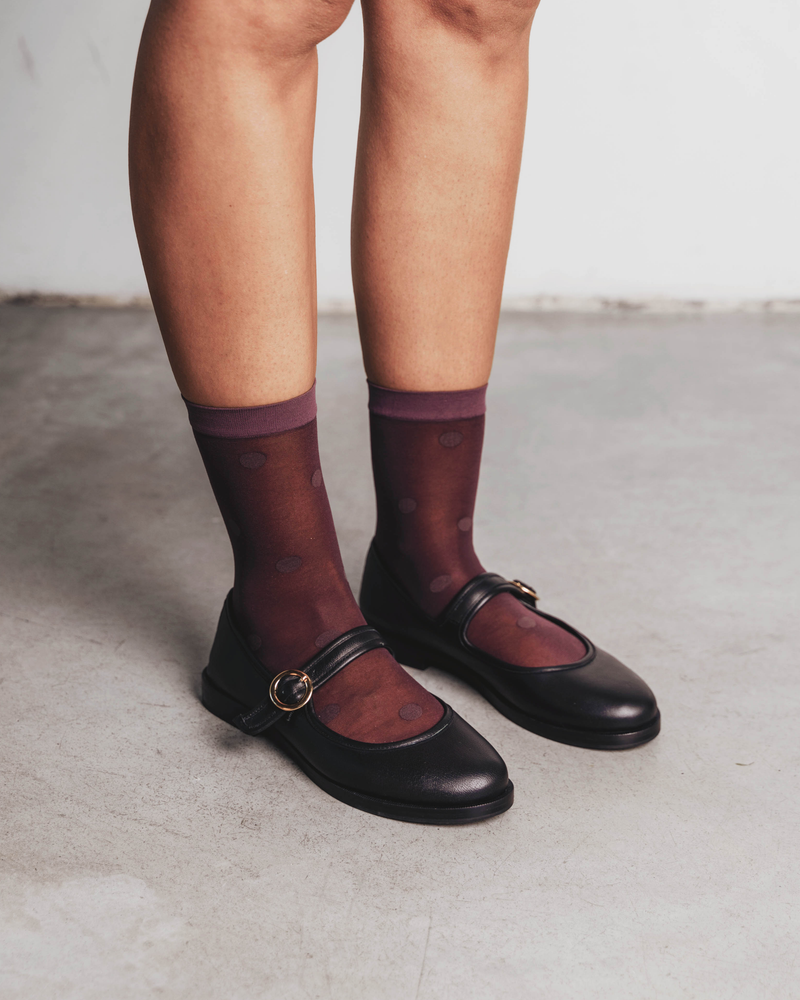 Close-up of feet in dotted sheer socks paired with mary jane flats. Rachel Mega Dot Sheer Socks in Plum.
