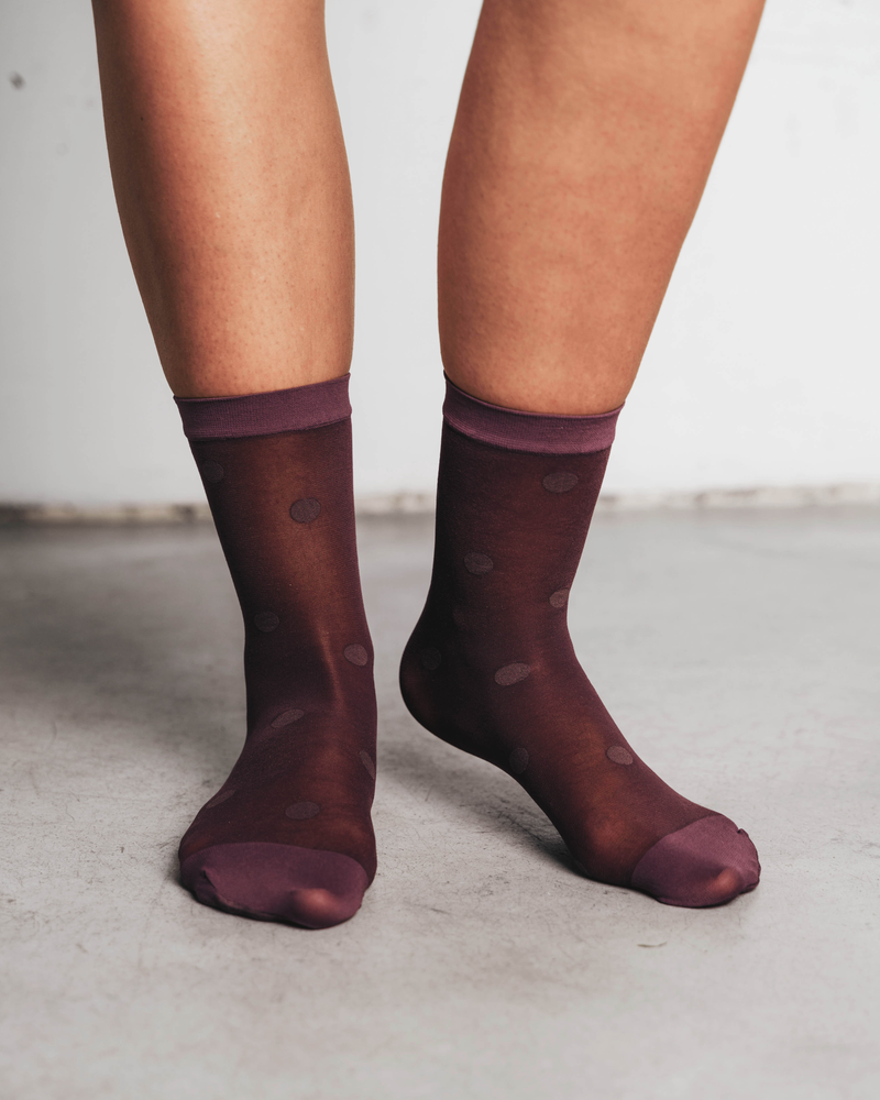Model's calves shown wearing sheer ankle socks with a dot pattern. Rachel Mega Dot Sheer Socks in Plum.
