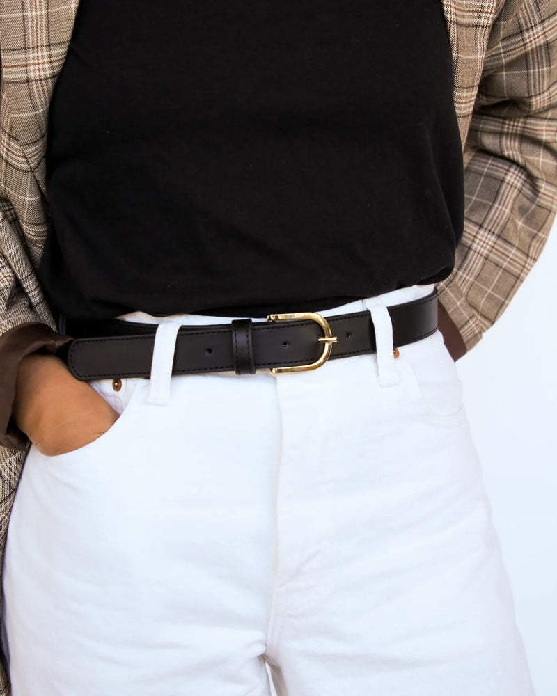 Black smooth leather belt with gold buckle, styled with white trousers and black top. The Accent Belt Gold Black.