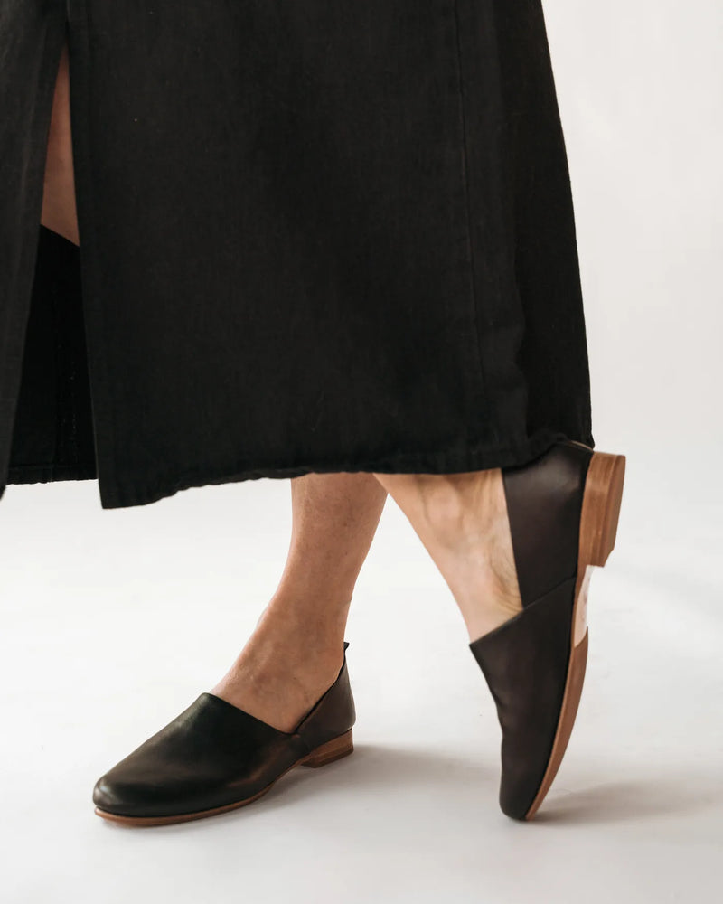 Leather slip-on shoes on woman midi skirt. The At-Leisure Slip-On 2.0 Black. Sizes 5–12, available in wide.