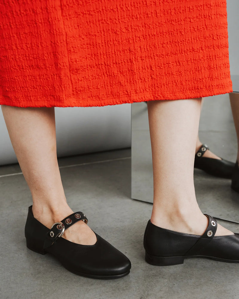 Leather Mary Janes with eyelet strap worn with red dress. The BLVD Mary Jane Black. Sizes 5–12, available in wide.