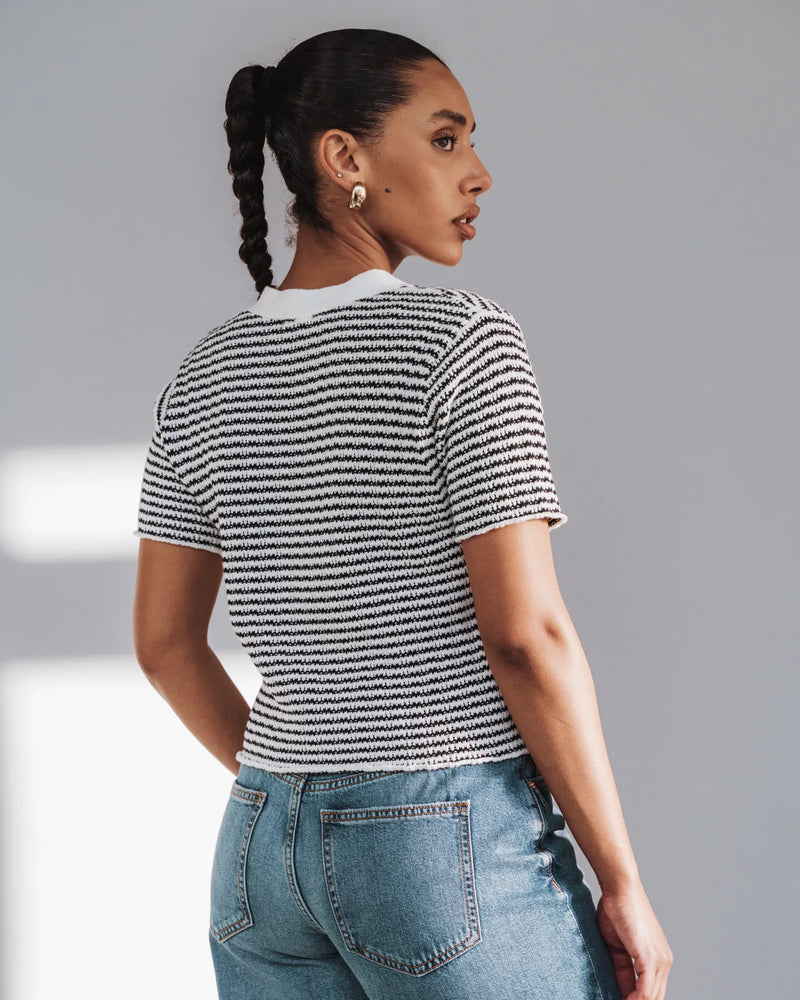 Back view of a woman wearing a black and white stripe short-sleeve knit cardigan. The Beach House Cardigan Black Stripe.