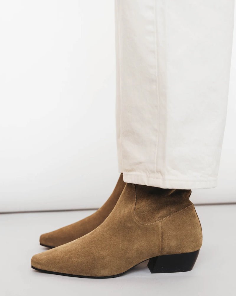 Side view of suede square-toe ankle boots worn with white jeans. The Beau Boot Desert Suede. Sizes 5–12.