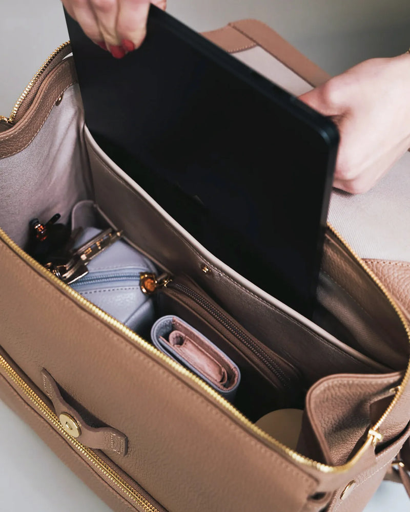 Open interior of the leather backpack with a laptop, pouch and wallet inside. The Beyond Backpack Biscotti.