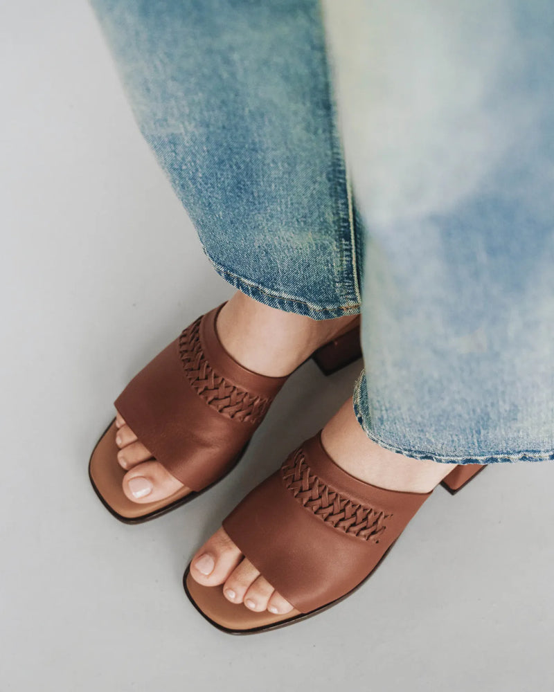 Leather heeled slides with woven detail, overhead view with jeans. The Bohème Heeled Sandal Hazelnut. Sizes 5–12.