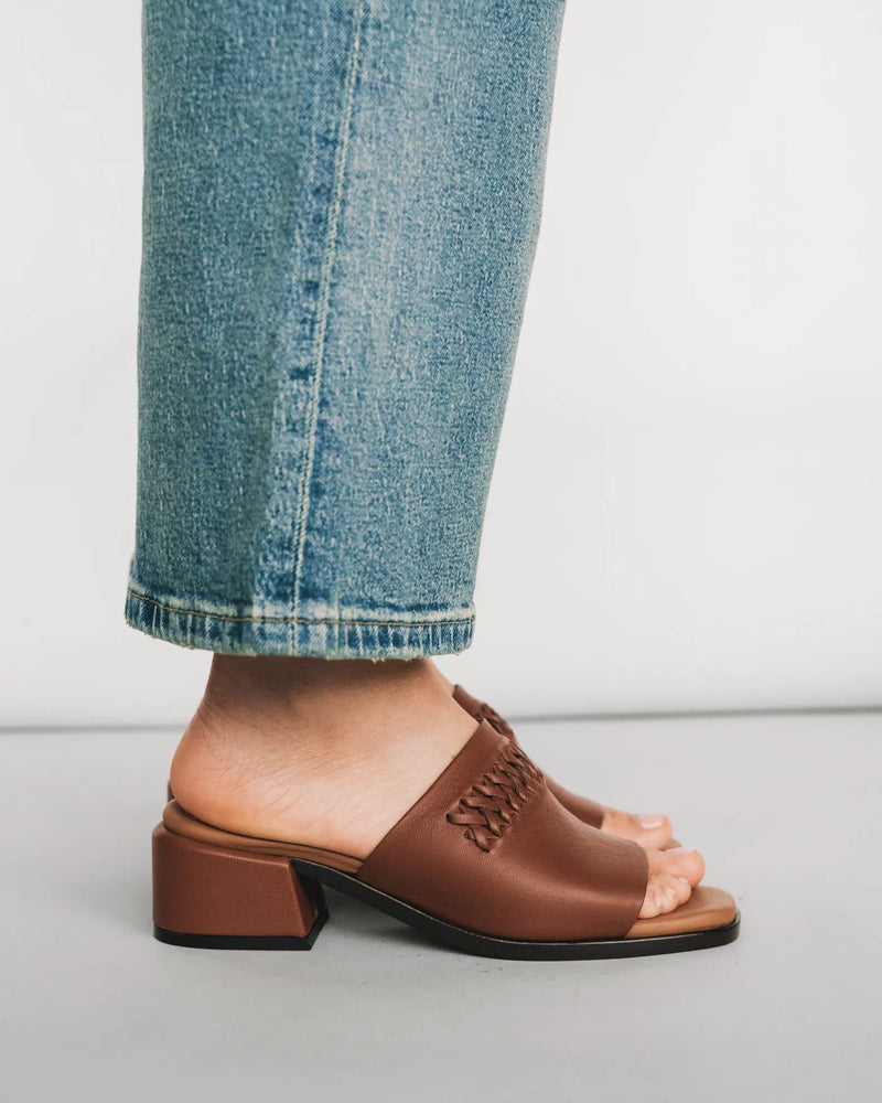 Leather heeled slides with woven detail, side view with light jeans. The Bohème Heeled Sandal Hazelnut. Sizes 5–12.