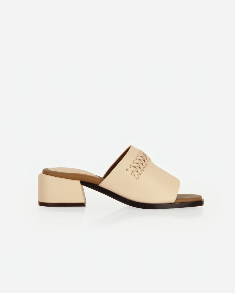 Side view of heeled slide sandal with woven strap and block heel. The Bohème Heeled Sandal Oat Milk. Sizes 5–12.