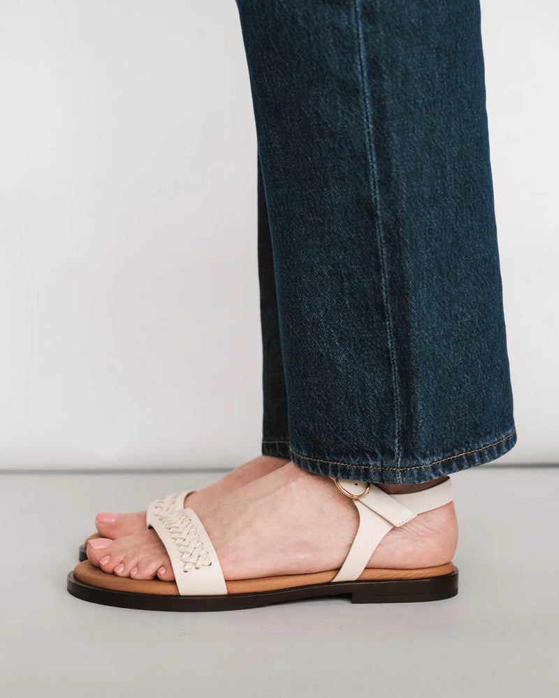 Woven leather sandals with ankle strap, side view with dark jeans. The Bohème Sandal Oat Milk. Sizes 5–12.
