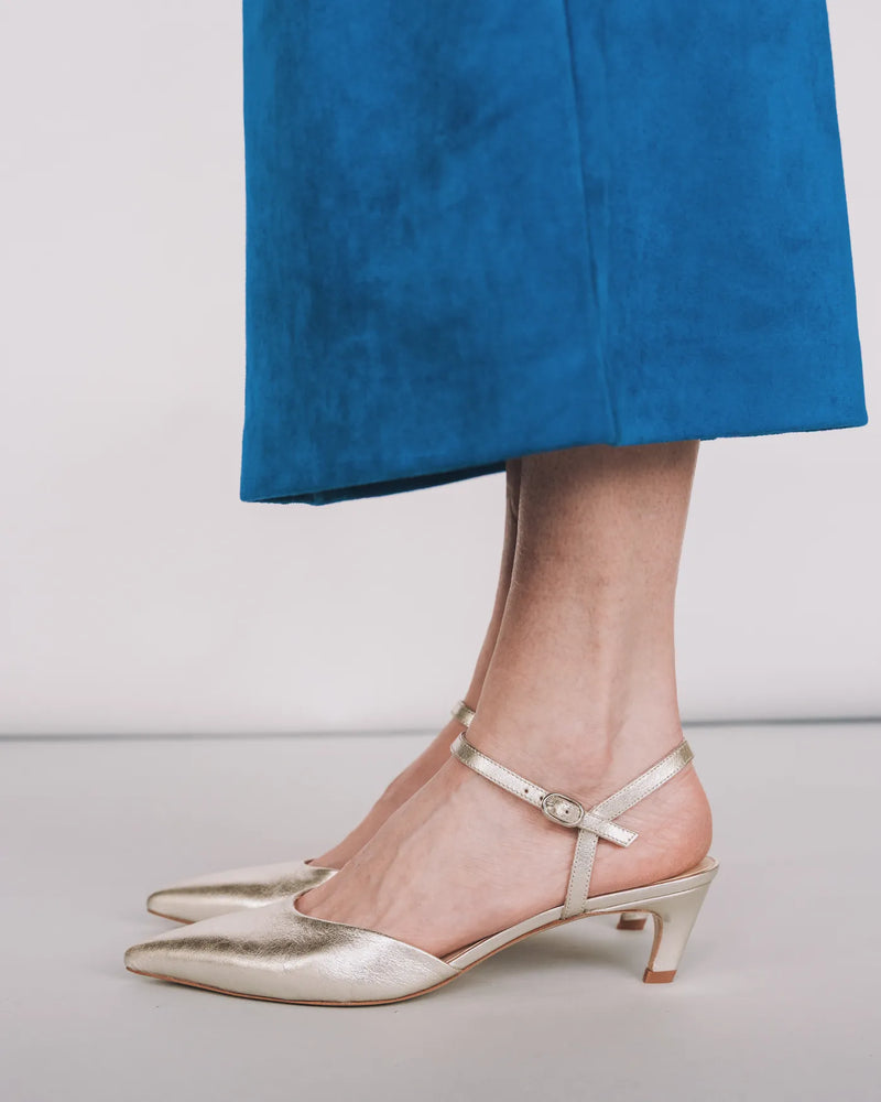 Silver crinkle kitten heels with ankle strap, worn with blue wide pants. The Claire Kitten Heel Silver Crinkle. Sizes 5–12.