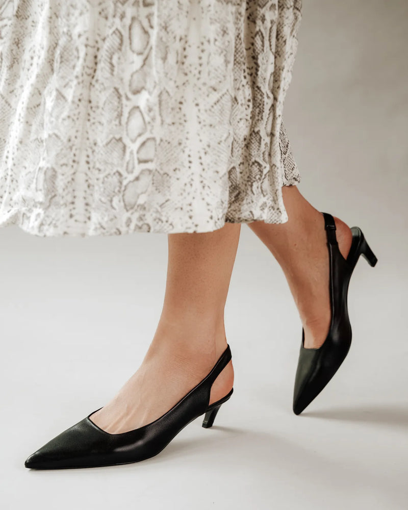 Woman in snake print skirt wears black kitten heel slingbacks. The Claire Slingback Black. Sizes 5–12, available in wide.