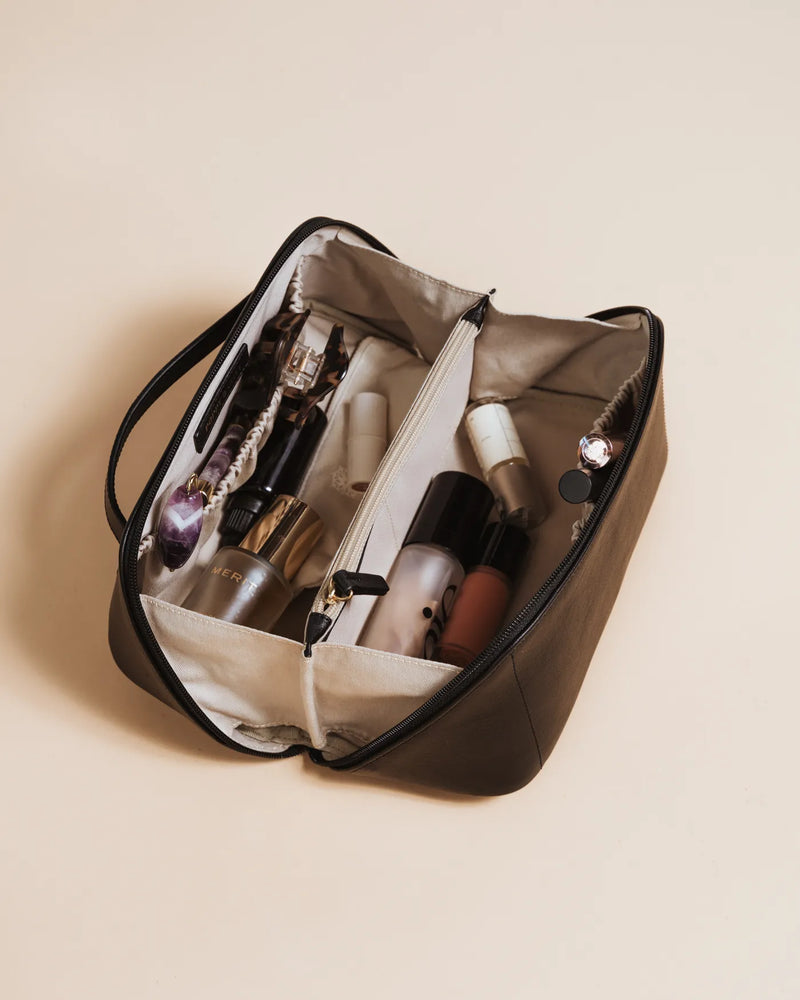 Large leather cosmetic case with two canvas compartments holding makeup and skincare. The Cosmetic Case Large Black.