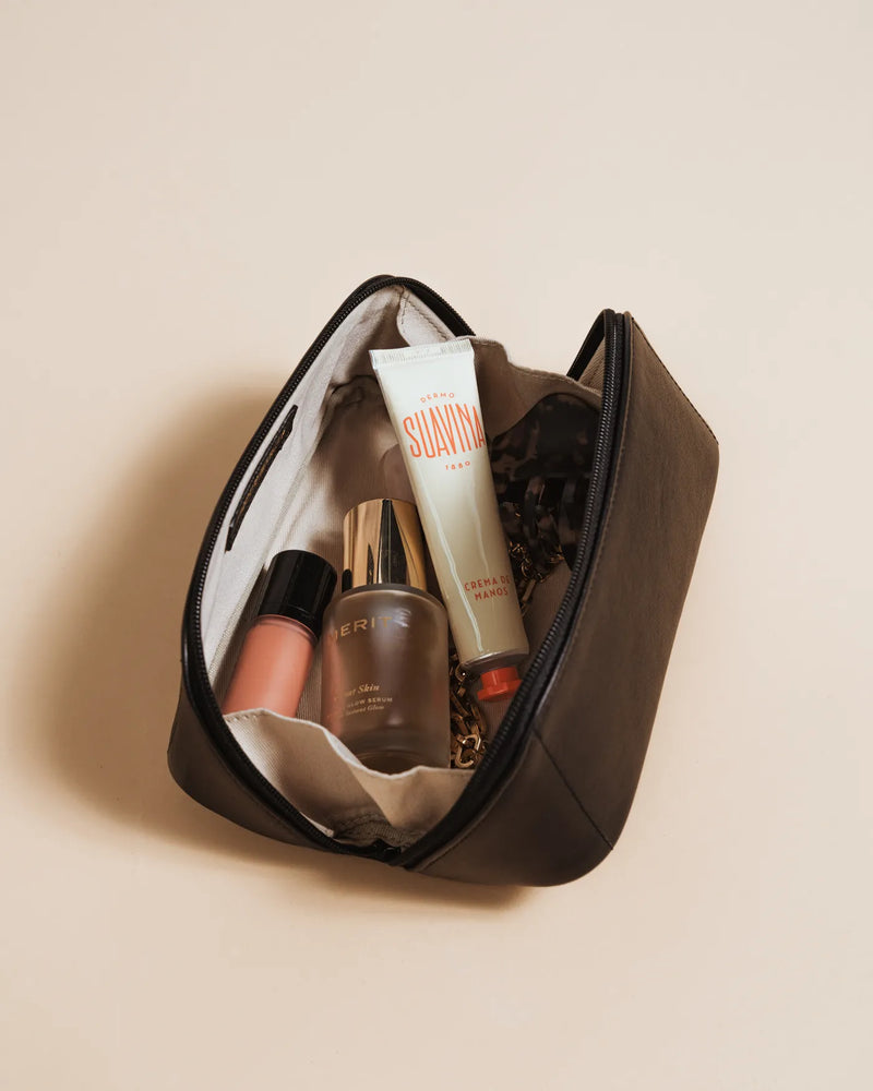 Open leather cosmetic case with canvas interior and skincare products. The Cosmetic Case Small Biscotti.