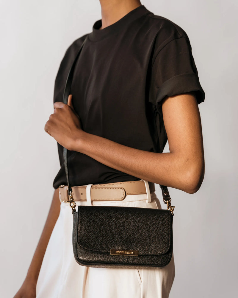 The Day To Night Bag Black Pebble in pebbled leather worn crossbody by woman in dark tee and cream trousers