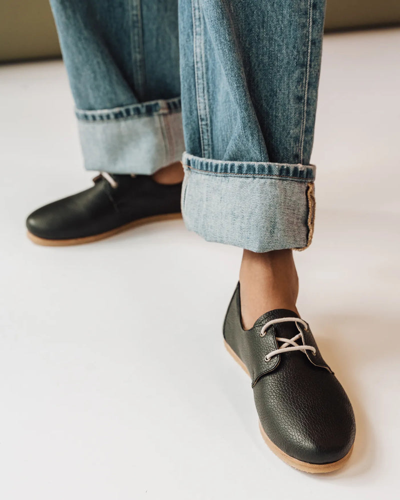 Woman in rolled jeans wearing The Eyelet Oxford 2.0 Black Pebble lace-up oxfords. Sizes 5–12, wide available.