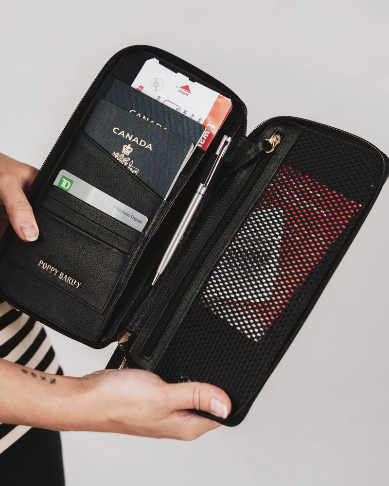 The Flying Solo Passport Holder Biscotti open, showing Canadian passport, cards and pen, held by woman in striped top