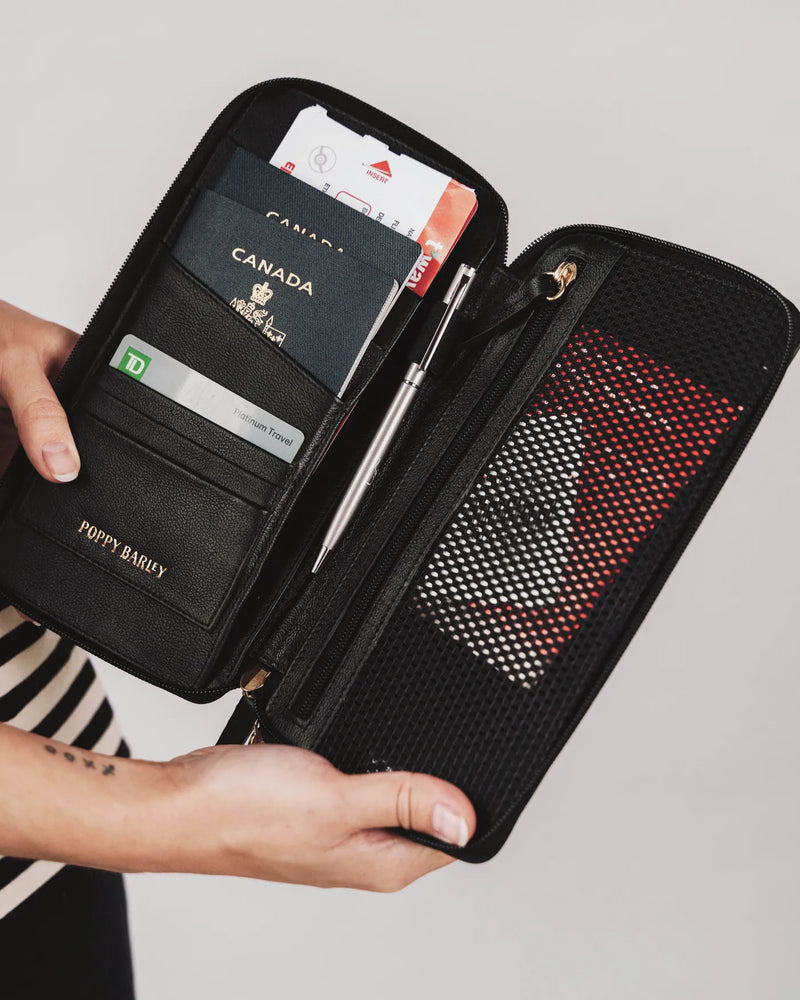 Open solo passport holder with passport and cards held by woman. The Flying Solo Passport Holder Black Micro Pebble.