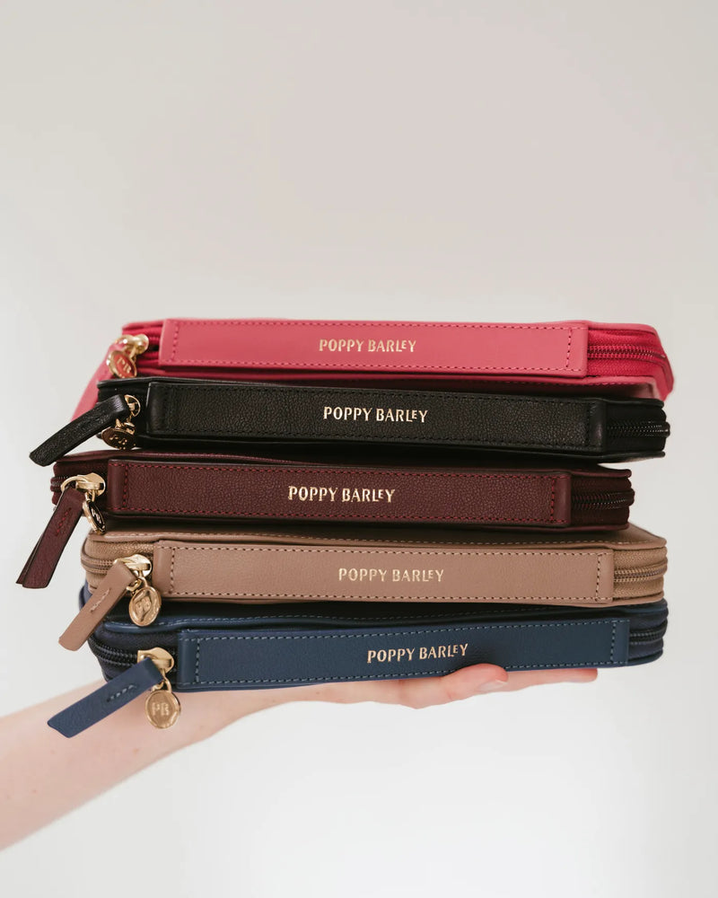 Stack of Poppy Barley leather passport holders in multiple colours. The Flying Solo Passport Holder Pacific Micro Pebble.