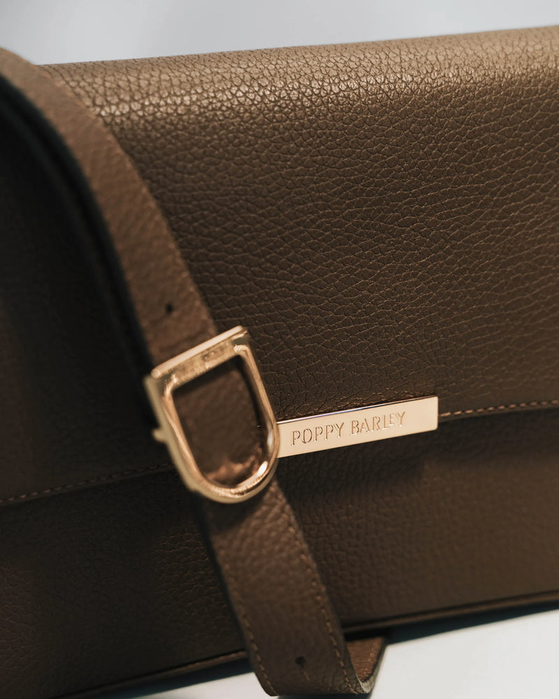 Close-up of tapenade shoulder bag with gold Poppy Barley logo and D-ring detail. The High Line Shoulder Bag Tapenade.