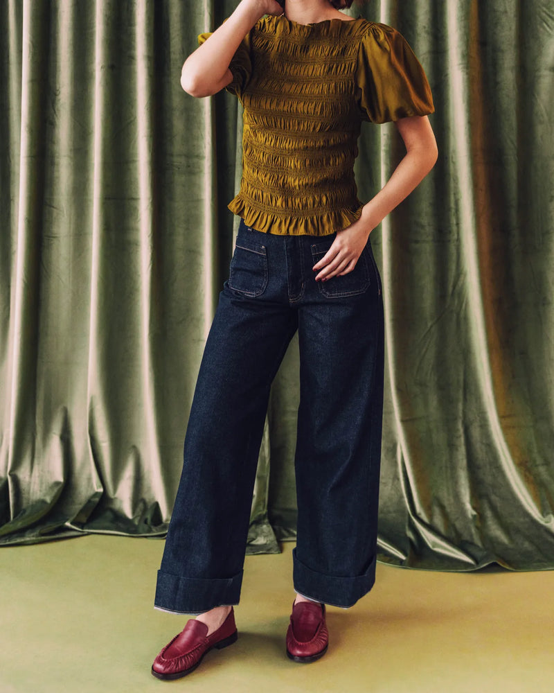 Woman in a smocked olive top and wide-leg jeans wearing loafers. The Laid Back Loafer Resort Red. Sizes 5–12.