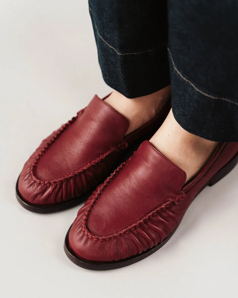 Leather loafers with ruched toe detail, worn with dark jeans. The Laid Back Loafer Resort Red. Sizes 5–12.