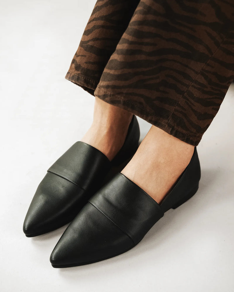 Woman in tiger-print pants wears black pointed-toe flat loafers. The Luxe Fit Flat Black. Sizes 5–12, available in wide.