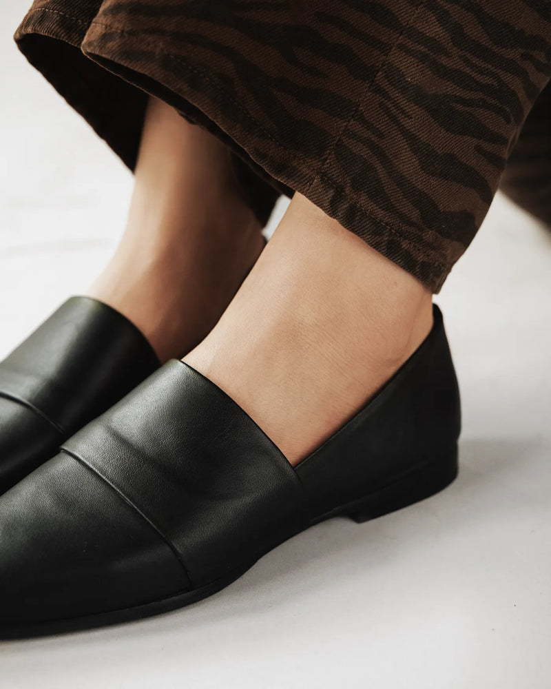 Close-up of black pointed-toe flat loafer with suede band panel. The Luxe Fit Flat Black. Sizes 5–12, available in wide.