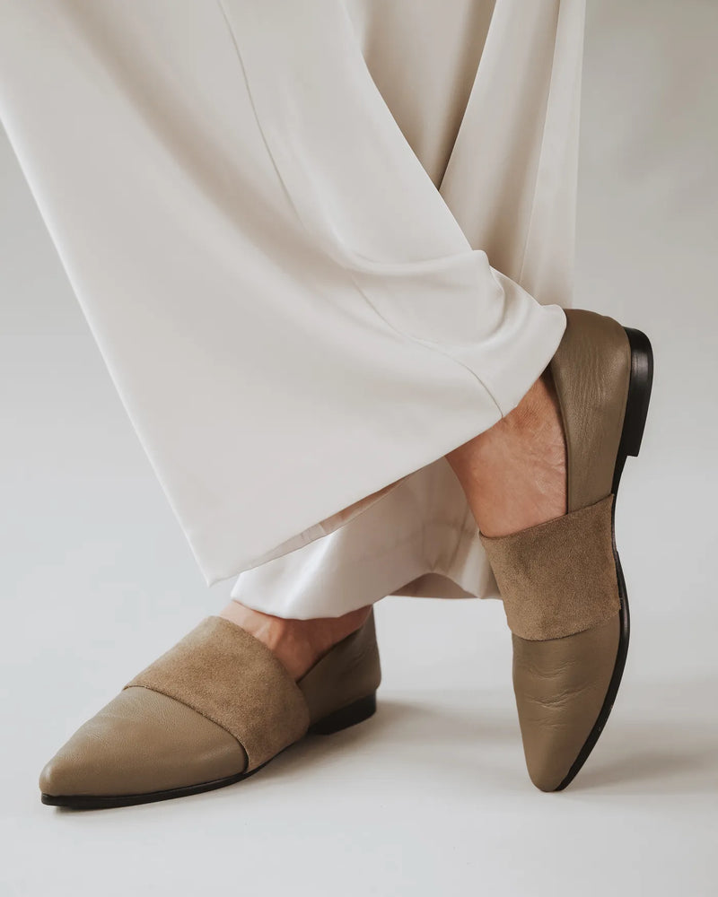 Woman in white wide-leg pants wears leather and suede pointed-toe flats. The Luxe Fit Flat Truffle. Sizes 5–12.