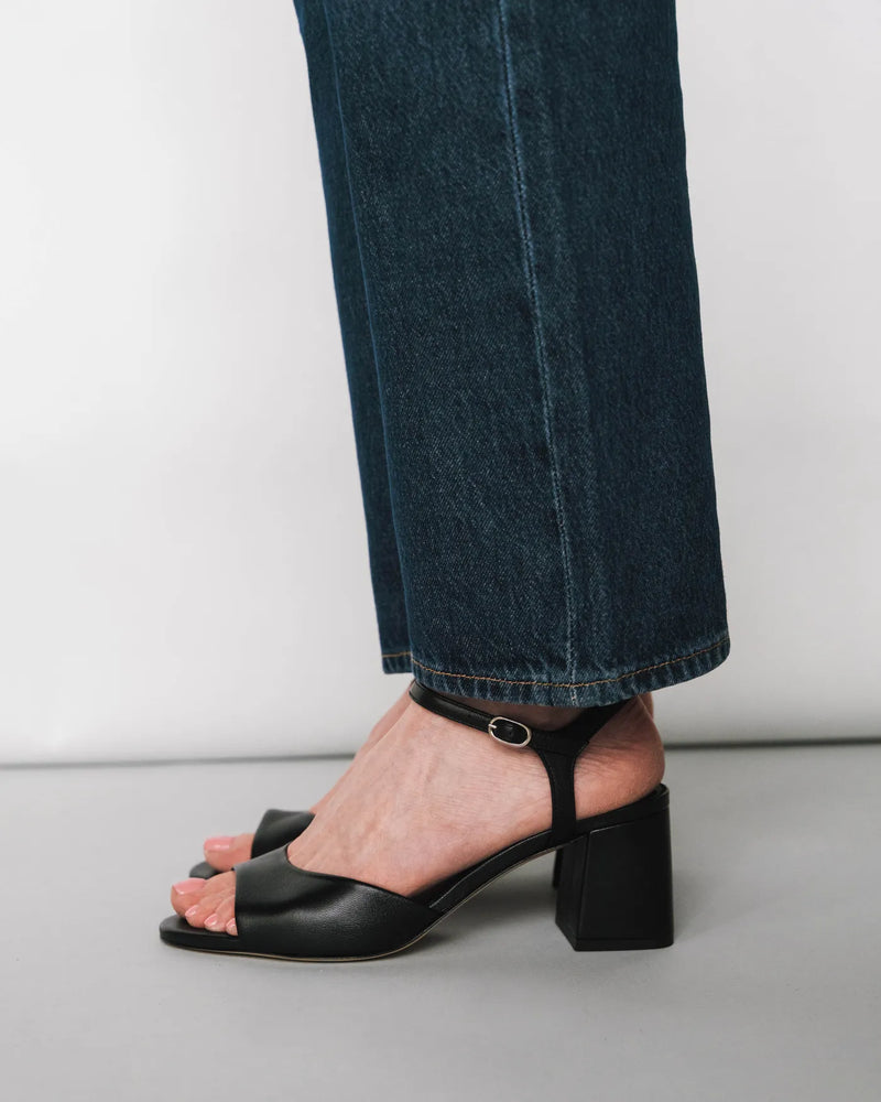 Leather block-heeled sandals with ankle strap, side view with dark jeans. The Mila Heeled Sandal Black. Sizes 5–12.