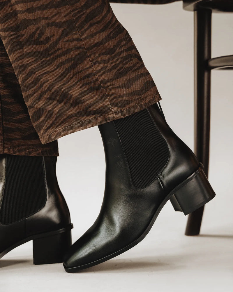 Woman in tiger-print pants wears leather square-toe chelsea boots. The Quinn Chelsea Boot Black. Sizes 5–12.