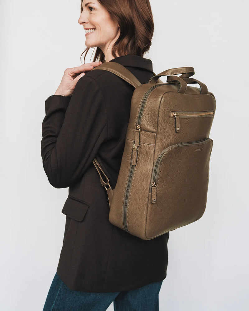 Pebbled leather backpack rear view on rolling suitcase, showing luggage sleeve. The Refined Backpack Tapenade.