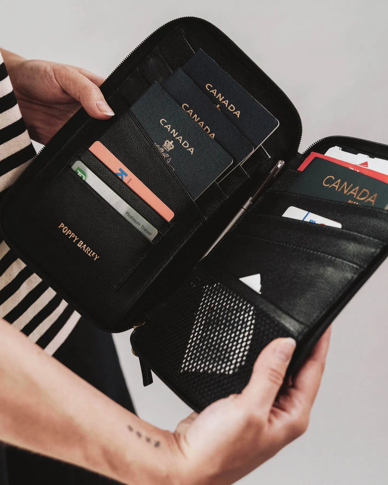 Open passport holder with multiple passports and cards inside. The Six Person Family Passport Holder Biscotti Micro Pebble.