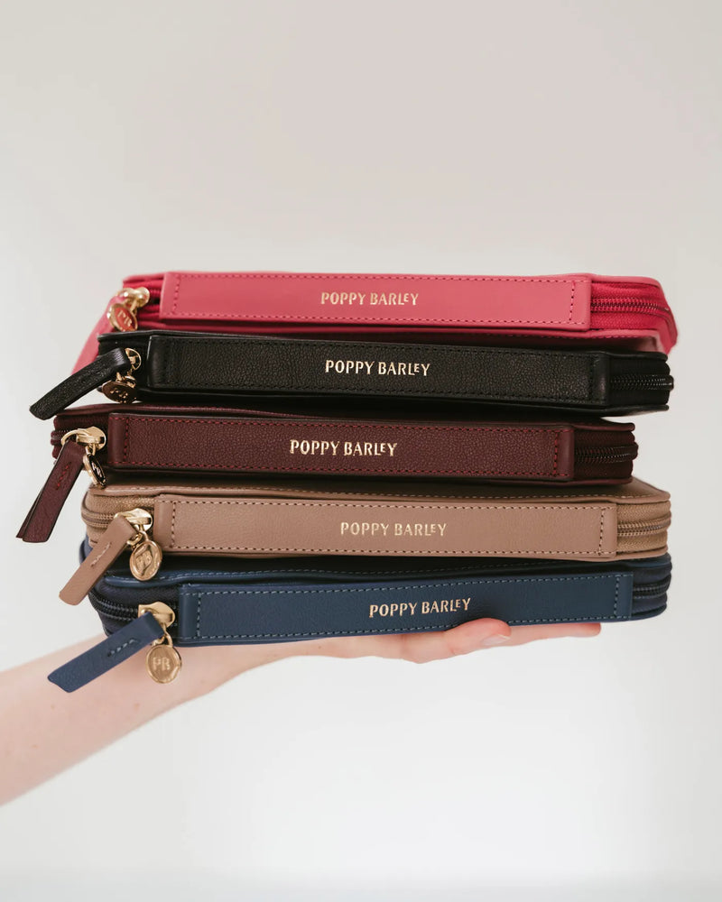 Stack of Poppy Barley passport holders in multiple colours. The Six Person Family Passport Holder Pacific Micro Pebble.