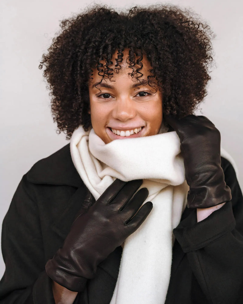 The Sleek Leather Glove Black in leather, worn by smiling woman with curly hair coat and white scarf